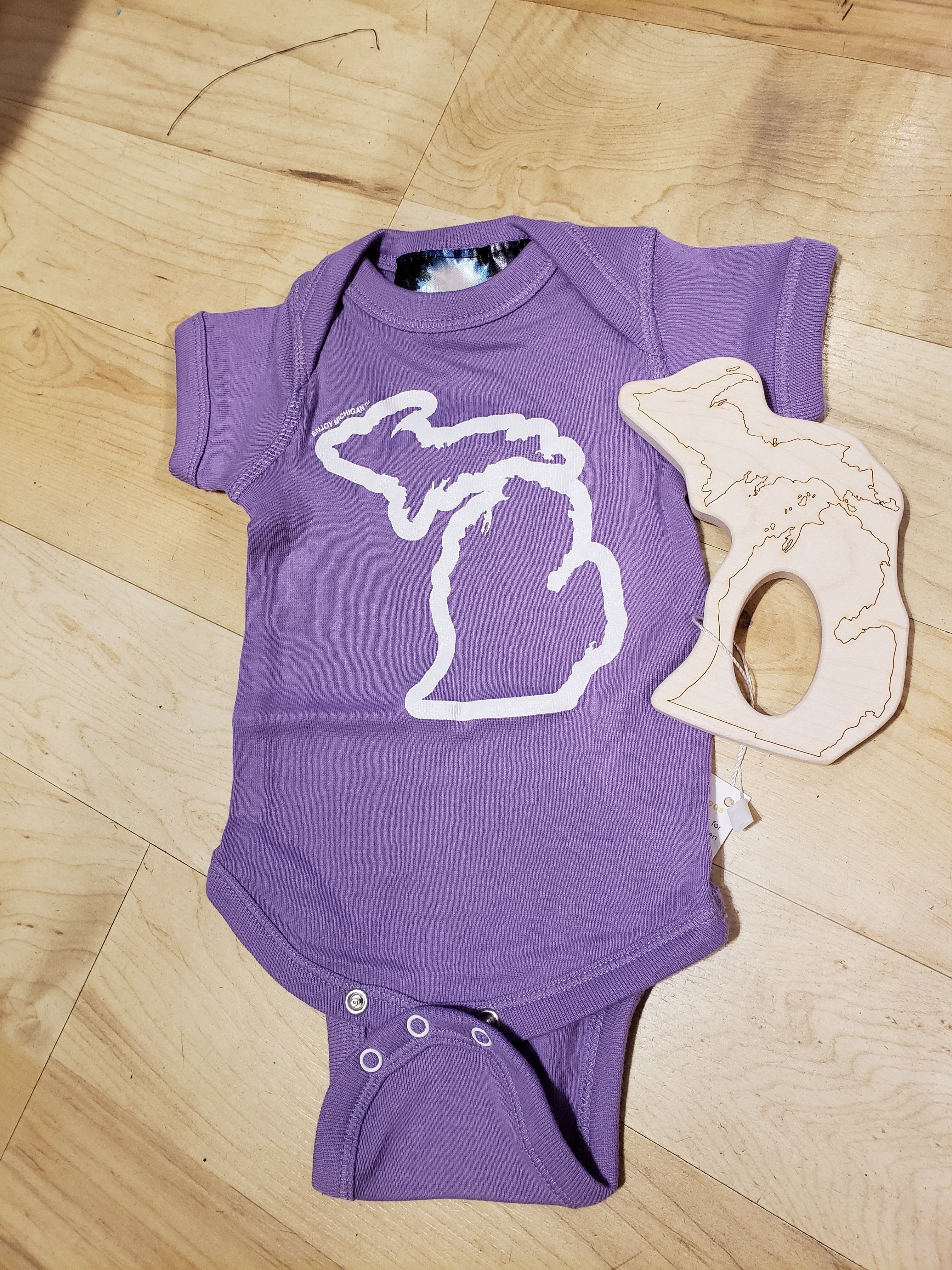 Enjoy Michigan Onesies in purple with a graphic of the state of Michigan outlined in white on the front